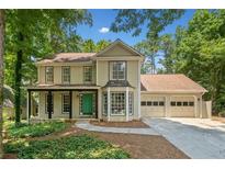 Charming two-story home with a manicured lawn, two-car garage, and inviting front porch at 5055 Southland Dr, Woodstock, GA 30188