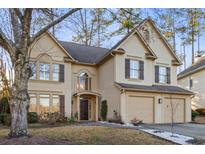 Charming two-story stucco home with a two-car garage, complemented by a well-maintained front yard and mature trees at 5105 Riverthur Pl, Duluth, GA 30096