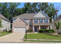 Charming two-story brick home featuring blue shutters, a landscaped yard, and a two-car garage at 1087 Halletts Peak Pl, Lawrenceville, GA 30044