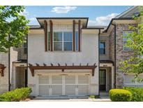 Charming townhome featuring a two-car garage, white brick facade, and manicured landscaping at 2058 Glenview Park Cir, Duluth, GA 30097