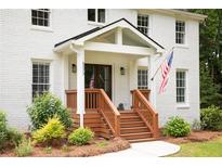 Inviting front porch with stained wood steps, American flag, and meticulously maintained landscaping at 5070 Hensley Dr, Atlanta, GA 30338