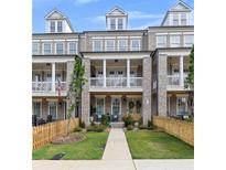 Charming townhouse featuring a brick facade, second-story balconies, manicured landscaping, and inviting entryways at 579 Brashy St, Woodstock, GA 30188