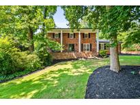 Beautiful two-story brick home with a well-manicured lawn, trees, and a welcoming front entrance at 285 Jade Cove Dr, Roswell, GA 30075