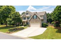 Charming two-story home with a well-manicured lawn, mature trees, and a spacious driveway leading to a two-car garage at 4345 Idlewood Dr, Cumming, GA 30040