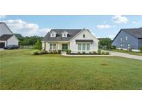 Charming modern farmhouse featuring a well-manicured lawn, black roof and a pair of rocking chairs at 4720 Down Setting Rd, Cumming, GA 30028