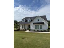 Charming white farmhouse with black roof, complemented by a well-manicured lawn and a walkway to the inviting front porch at 4720 Down Setting Rd, Cumming, GA 30028