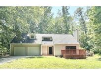 Charming home featuring an attached garage and a wooden porch, surrounded by lush greenery at 5968 Hilltop Dr, Douglasville, GA 30135