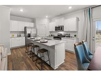 A bright kitchen with an island, granite countertops, stainless steel appliances, and hardwood floors at 4948 Jatoba Rd, Acworth, GA 30101