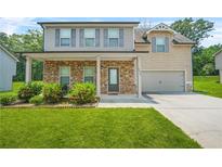 Charming two-story home with stone accents, covered porch, lush lawn and mature landscaping at 588 Joneus Dr, Mcdonough, GA 30252