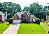 Charming brick home with a well-manicured lawn and lush landscaping at 830 Club Chase Ct, Roswell, GA 30076