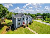 Two-story home boasts a manicured lawn, a red door, and mature trees surrounding the property at 11 Chad Ct, Mcdonough, GA 30253