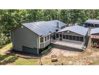 A rear exterior view shows a metal roof, enclosed porch, open deck and wooded lot at 261 Clayton Trl, Canton, GA 30114