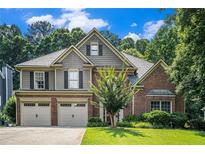 Charming two-story home featuring a brick and siding exterior, well-manicured lawn, and an attached two-car garage at 3117 Blowing Wind Nw Ct, Acworth, GA 30101