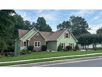 Charming home with a stone facade and red shutters on a well-manicured lawn at 4185 Lenox Park Dr, Buford, GA 30519