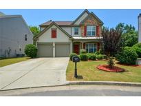 Charming two-story home featuring a manicured lawn, stone accents, and a two-car garage at 574 Friars Head Dr, Suwanee, GA 30024