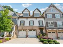Charming brick and siding townhome with two-car garage and landscaped front, under a sunny sky at 214 Trecastle Sq, Canton, GA 30114