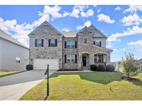 Beautiful two-story brick home featuring a two-car garage and manicured front yard at 7410 Ansley View Ln, Cumming, GA 30028