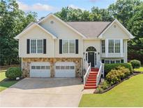 Charming split-level home with stone accents, two-car garage and inviting, red-painted staircase at 2355 Woodland Hills Dr, Cumming, GA 30040