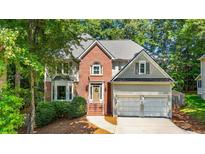 Charming two-story home featuring a brick facade, two-car garage, and lush landscaping at 120 Ashewoode Downs Ln, Alpharetta, GA 30005