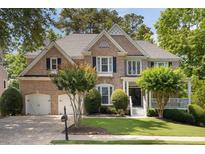 Charming two-story brick home with a well-manicured lawn, mature trees, and a two-car garage at 2030 Darien Park Dr, Roswell, GA 30076