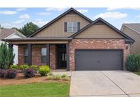 Charming brick and siding home with a covered front porch and attached two-car garage at 115 Court Xing, Locust Grove, GA 30248