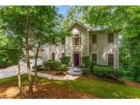 Charming home featuring a stucco exterior, lush landscaping, and a welcoming purple front door at 1950 Wenlok Ne Trl, Marietta, GA 30066