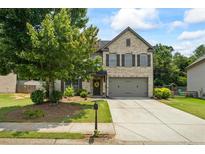 Charming two-story home featuring a well-manicured lawn, a brick facade, and a welcoming front porch at 4275 Hunters Walk Way, Cumming, GA 30028