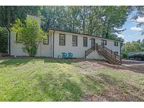 Charming painted brick home featuring a side entrance with wooden stairs and a lush front lawn at 3924 Devonshire Dr, Marietta, GA 30066