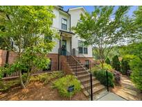 Charming two-story townhouse with brick accents, lush landscaping, and inviting stairway to the front door at 219 Phillips Ln, Alpharetta, GA 30009