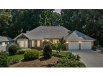 Charming brick home with a well-manicured lawn and a two-car garage nestled amongst mature trees at 5195 Overbend Trl, Suwanee, GA 30024