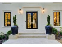Elegant front entrance with black double doors, modern lighting, and potted greenery on a white brick facade at 6090 River Chase Cir, Atlanta, GA 30328