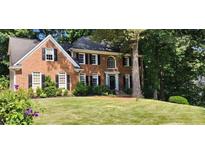Elegant two-story brick home with manicured lawn, black shutters and a charming entrance framed by lush greenery at 4971 Fairhaven Ne Way, Roswell, GA 30075