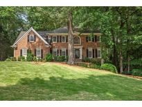 Stately brick home boasts lush lawn, mature trees, classic black shutters and well-maintained landscaping at 4971 Fairhaven Ne Way, Roswell, GA 30075