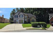 Two story home with a brick and stucco front, green lawn, and two car garage at 3310 Mcclure Woods Ct, Duluth, GA 30096