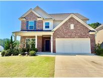 Two-story brick home featuring a two-car garage and a well-manicured lawn with flowering bushes at 5599 Wheeler Ridge Rd, Auburn, GA 30011