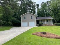 Charming home featuring a two-car garage, well-manicured lawn, and mature trees at 7562 Asbury Manor Dr, Lithonia, GA 30014