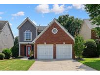 Charming two-story home with a red brick and gray siding, with a two-car garage and well-maintained lawn at 1265 Birchwood Ln, Roswell, GA 30076