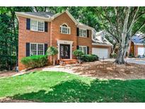 Traditional two-story brick home with a lush green lawn and mature trees at 10575 Tuxford Dr, Alpharetta, GA 30022