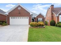 Charming brick home featuring a two-car garage, manicured lawn, and mature landscaping at 2323 Blackberry Ct, Snellville, GA 30078