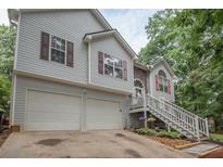 Charming two-story home features a two-car garage and inviting front porch, set amongst lush greenery at 241 Lost Lake Way, Villa Rica, GA 30180