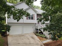 Charming home featuring a two-car garage, stone accents, a cozy front porch, and well-maintained landscaping at 241 Lost Lake Way, Villa Rica, GA 30180
