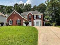 Charming two-story red brick home with a well-manicured lawn and a curved driveway at 134 Carolinas Way, Fayetteville, GA 30215