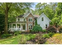 Charming two-story home features a stone facade and a welcoming front porch surrounded by lush landscaping at 1788 River Bluff Vw, Duluth, GA 30097