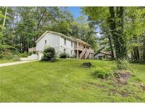 The exterior view of a two-story home with a large front yard and lots of trees at 537 Raven Springs Trl, Stone Mountain, GA 30087