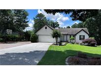 Charming single-story home with a lush green lawn and an inviting driveway with basketball hoop at 1570 Cedars Rd, Lawrenceville, GA 30045