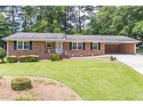 Charming brick home with manicured lawn, black shutters, and covered carport at 4077 Phils Ct, Tucker, GA 30084