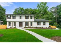 Charming two-story home with white brick, dark shutters, and a well-manicured lawn at 4555 Holliston Rd, Dunwoody, GA 30360