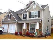 Charming two-story home with stone accents, beige siding, dark shutters, and a welcoming front porch at 2481 Southhaven Ln, Buford, GA 30519