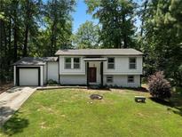 Charming home featuring a manicured lawn, attached garage, and a striking red front door at 3267 Sunderland Dr, Snellville, GA 30039