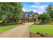 Stunning stone home featuring a curved driveway, three-car garage, and professionally landscaped yard at 4239 Lower Jersey Rd, Covington, GA 30014